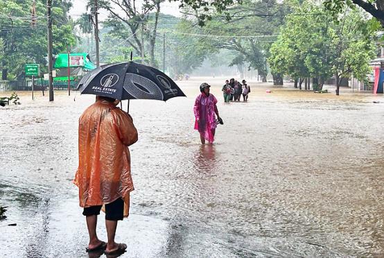 People walk through floodwaters covering a street in Myitkyina, Myanmar. PHOTO: AFP
