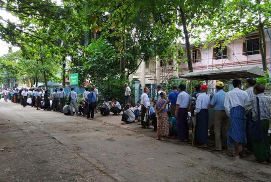 Retired civil servants wait to receive their pensions in front of the Myanma Economic Bank.