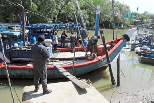 Aksem personnel inspecting a fishing boat at a jetty in Kampung Seberang Jaya in Kuala Perlis./The Star