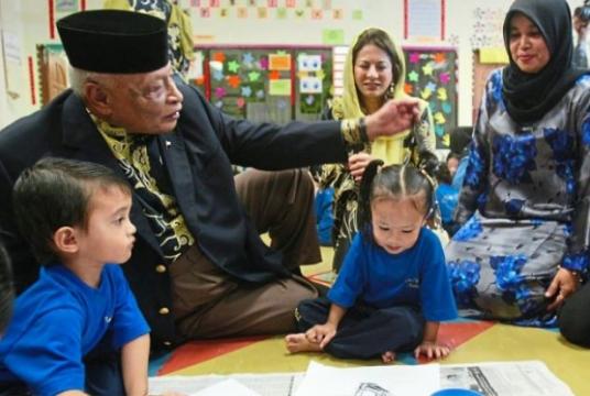 The late Sultan Ahmad Shah with two children at a nursery centre in Kuantan in this 2011 file picture. Looking on is (centre) Sultanah Hajah Kalsom./The Star