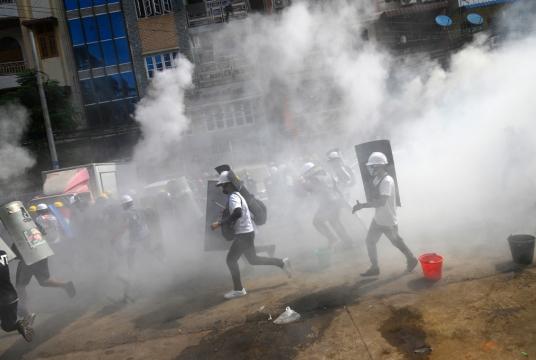 Protesters hold homemade shields as they run during a demonstration against the military coup in Yangon on March 3, 2021. (Agence France Presse/STR)