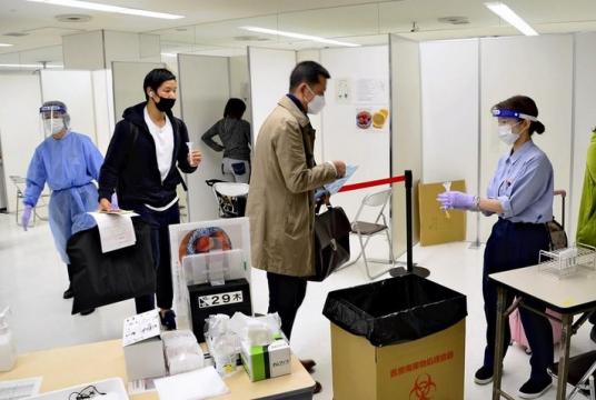 A traveler hands a test tube containing saliva to an official at the quarantine inspection station at Narita Airport on October 30.