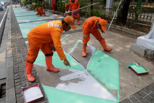 Workers paint the sidewalk near the National Monument in Central Jakarta on July 30, 2017. (JP/Wendra Ajistyatama)