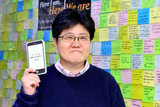 Cho Jin-kyeong holds up a Teens Up in front of a wall in her office full of messages of support for victims of underage prostitution. (Park Hyun-koo / The Korea Herald)