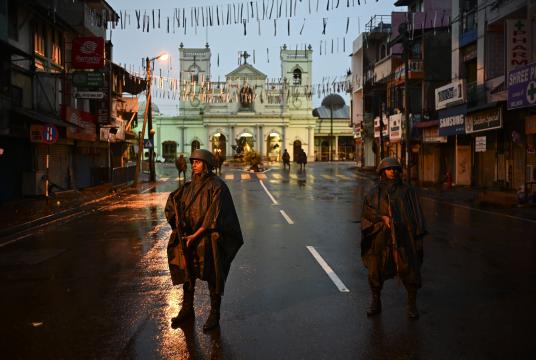 Sri Lankan soldiers stand guard under the rain at St. Anthony's Shrine in Colombo on April 25, 2019, following a series of bomb blasts targeting churches and luxury hotels on the Easter Sunday in Sri Lanka. - Sri Lanka's Catholic church suspended all public services over security fears on April 25, as thousands of troops joined the hunt for suspects in deadly Easter bombings that killed nearly 360 people. (Photo by Jewel SAMAD / AFP)