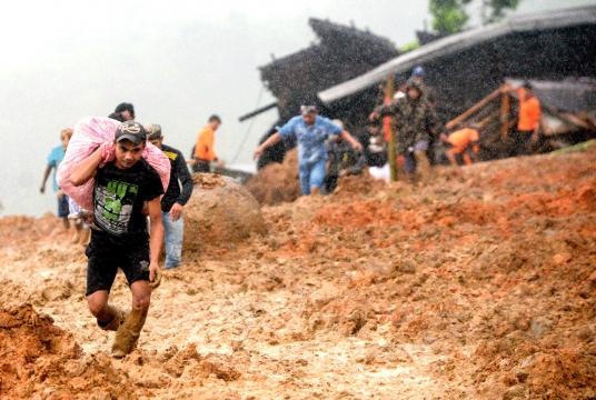 Grim task: Residents flee their homes as rescue workers search for survivors at the site of a landslide in Sukabumi, West Java, on Tuesday. The landslide, which was triggered by heavy rain, left at least nine people dead and dozens missing. (AFP)