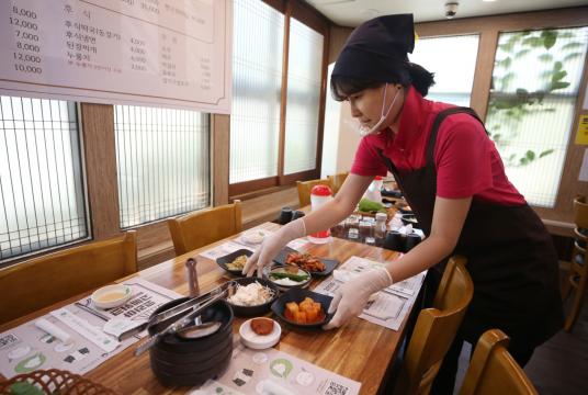 Photo shows a server at a restaurant in Gwangju wearing gloves and a plastic face shield as coronavirus countermeasures. (Yonhap)