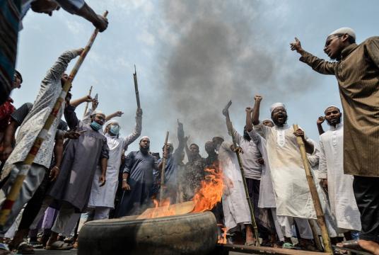 Activists from Hefazat-e Islam set fire to a tire and block a road during a nationwide strike following deadly clashes with police over Indian Prime Minister Narendra Modi’s visit, in Narayanganj, about 16 km southeast of Dhaka on March 28, 2021. (AFP/Munir uz Zaman)