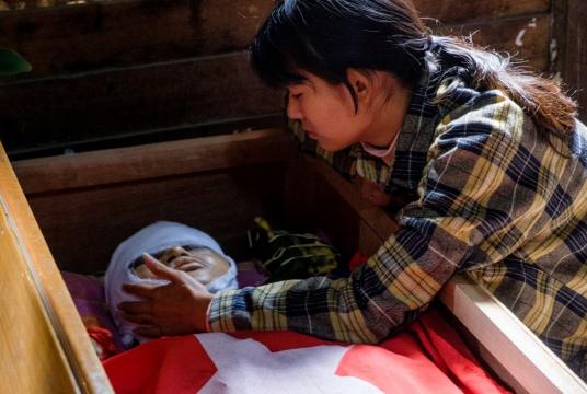 A relative touches the face of a protester, who died amid a crackdown by security forces on demonstrations against the military coup, during his funeral in Taunggyi in Myanmar's Shan state on March 29. (AFP/STR)