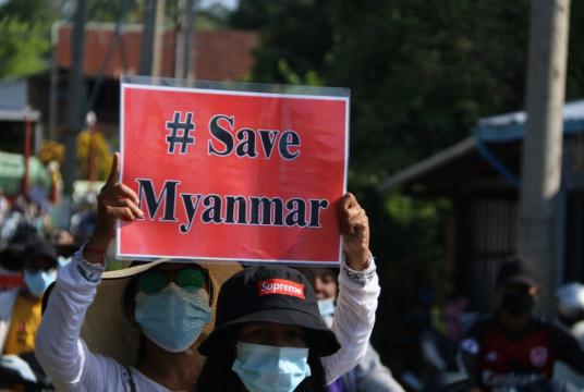 This handout photo taken and released by Dawei Watch on April 6, 2021 shows a protester holding a sign during a rally against the military coup in Launglone township in Myanmar's Dawei district. (Dawei Watch via AFP/Handout)