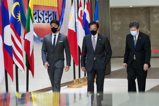 Brunei's Sultan Hassanal Bolkiah (center) and ASEAN Secretary-General Lim Jock Hoi (right) walk while attending the ASEAN leaders' summit at the bloc's secretariat building in Jakarta on April 24, 2021. (Handout/Muchlis Jr/Indonesian Presidential Palace via REUTERS)