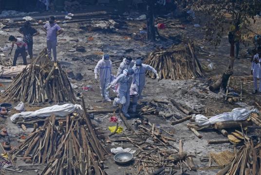 Family members and relatives perform the last rites amid the funeral pyres of victims who died of the Covid-19 coronavirus during mass cremation held at a crematorium in New Delhi on April 27, 2021. (AFP/Prakash Singh)