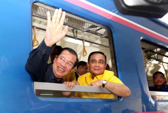 Cambodia's Prime Minister Hun Sen (L) waves beside Thailand's Prime Minister Prayut Chan-O-Cha as they ride a train during a ceremony to connect the railway line between Cambodia and Thailand in Banteay Meanchey province on April 22, 2019. // AFP