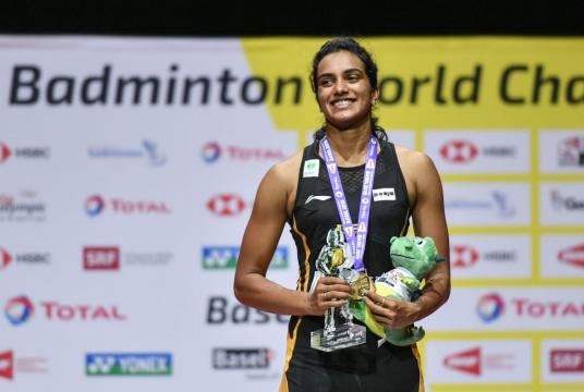 First-placed India's Pusarla Venkata Sindhu poses on with the gold medal during the podium cermony after her victory over Japan's Nozomi Okuhara during their women's singles final match at the BWF Badminton World Championships at the St Jakobshalle in Basel on August 25, 2019. (Photo by FABRICE COFFRINI / AFP)