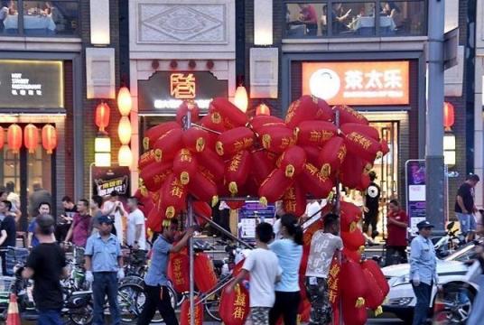 Workers carry red lanterns for decorating a night market at Beixinqiao area in Beijing, capital of China, Aug 7, 2019. (LI XIN / XINHUA)