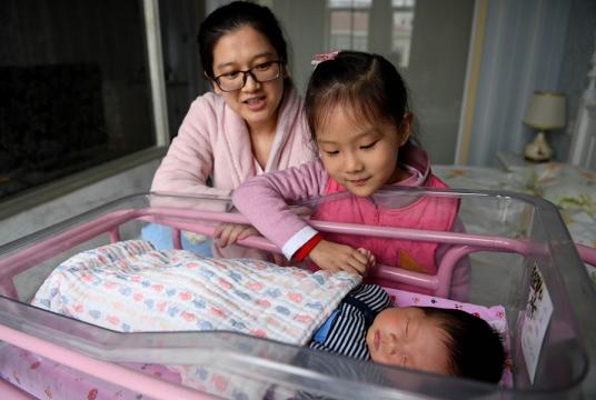 A mother and her daughter watch over the family's newborn baby at an infant healthcare center in Hefei, Anhui province, on Dec 2. [Photo/Xinhua]