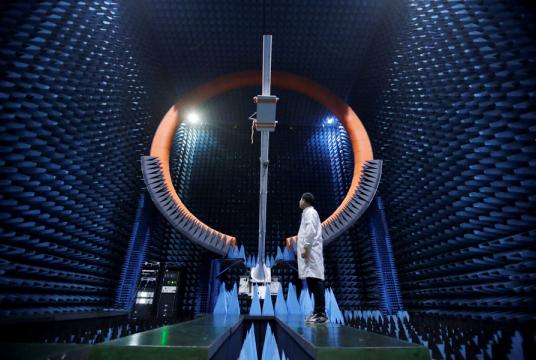 An engineer stands under a 5G base station antenna in Huawei’s Songshan Lake Manufacturing Center in Dongguan, Guangdong province, on Thursday. [Photo/Agencies]
