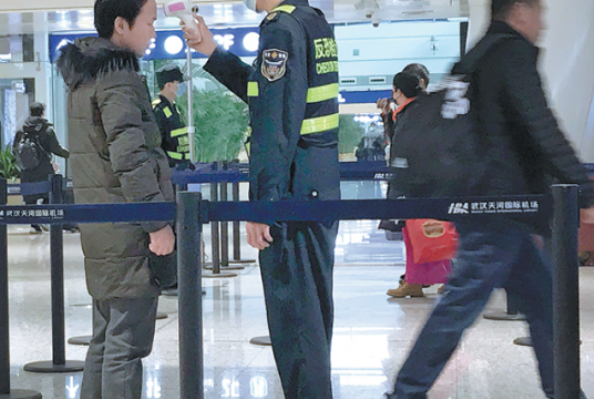 An official uses an infrared thermometer on a passenger at a health screening checkpoint at Wuhan Tianhe International Airport in Wuhan, Hubei province, on Tuesday. EMILY WANG / AP
