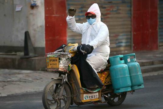 A worker, covering himself with a mask, glasses and a protective suit, delivers gas in the Jiang'an district of Wuhan, capital of Central China's Hubei province, on Feb 1. [Photo by Zhou Guoqiang/for chinadaily.com.cn]