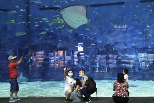 Parents and children take a selfie at the Beijing Aquarium, the largest of its size in the capital city, on Friday as the facility opened to the public for the first time since being closed for 133 days due to the novel coronavirus pandemic. ZOU HONG/CHINA DAILY