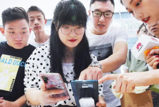 Consumers try the Huawei Mate 20X 5G, the first 5G smartphone produced by Huawei Technologies Co, at a China Mobile outlet in Beijing in August. WANG ZHUANGFEI/CHINA DAILY