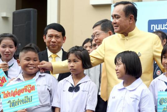 Prime Minister General Prayut Chan-o-cha teases a young beneficiary of the Equitable Education Fund (EQF) that provides scholarships for low-income children, as EQF chair Prasarn Trairatvorakul looks on at Government House yesterday./The Nation