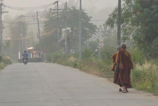 Monks walks through smog in Mae Hong Son’s Muang district yesterday to collect morning alms.