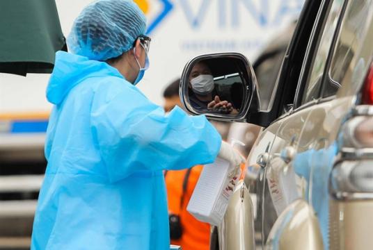 A medical worker sprays a hospital visitor with sanitiser. — Photo nld.com.vn