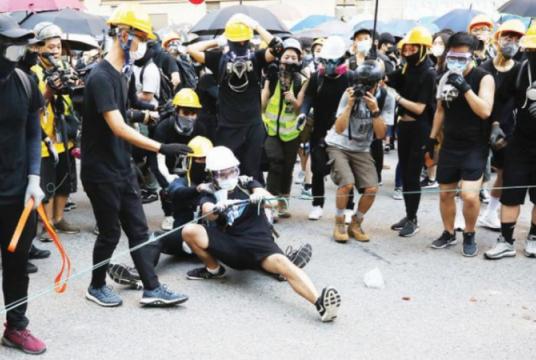 Protesters use a giant slingshot to shoot bricks and stones into Tsuen Wan Police Station on Aug 5, 2019. [Photo/China Daily]