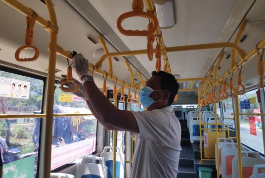A man disinfects a bus from Ludu's Partner Public Co. (Photo-Theingi Win Tun)