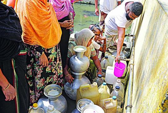 Locals of East Dholaipar queue up their pitchers, jerrycans, and bottles at a pump station to collect water. The area suffers from poor supply of water. The photo was taken recently. Photo: Palash Khan
