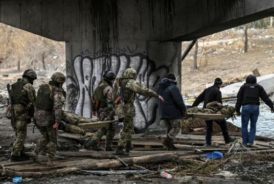 Ukranian servicemen carry the body of comrades on stretchers in the city of Irpin, northwest of Kyiv, on March 13, 2022. PHOTO: AFP