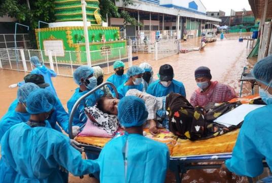 Volunteers carry a Covid-19 patient lying on a hospital bed during a flood in Myawaddy, Myanmar, on July 26, 2021.PHOTO: REUTERS