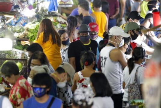 Men wearing protective masks buy food as people rush before the Munoz market closes for its morning business as they cut their operations to four hours a day as part of the enhanced community quarantine to prevent the spread of the new coronavirus in Metro Manila Thursday, March 19, 2020.  (Photo by AARON FAVILA / AP)
