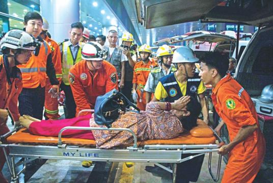Rescue workers carrying an injured passenger on a stretcher after a Biman aircraft slipped off the runway at Yangon International airport yesterday. Photo: AFP