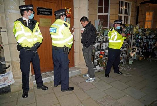 Myanmar's ambassador to the UK, Kyaw Zwar Minn, waits unsuccessfully for an answer on the intercom, as police officers stand on duty outside the Myanmar Embassy in London on April 7, 2021.PHOTO: AFP