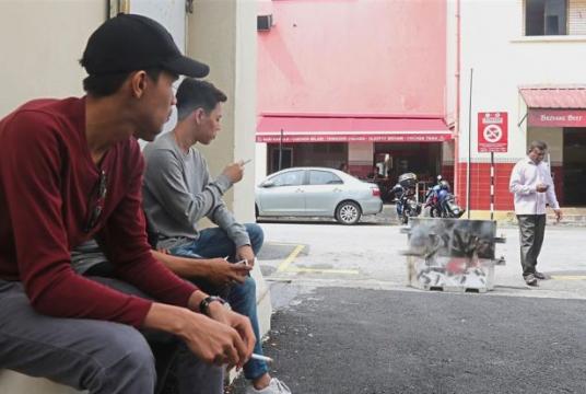  Keeping their distance: Hariz (left) and his friends smoking opposite a restaurant in Pitt Lane, George Town.