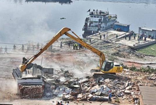 A bulldozer knocks down an illegal structure on the Buriganga during an eviction drive by the BIWTA in Kamrangirchar's Ashrafabad area yesterday. The authorities carried out the drive to stop river grabbing by influential people. Photo: Anisur Rahman