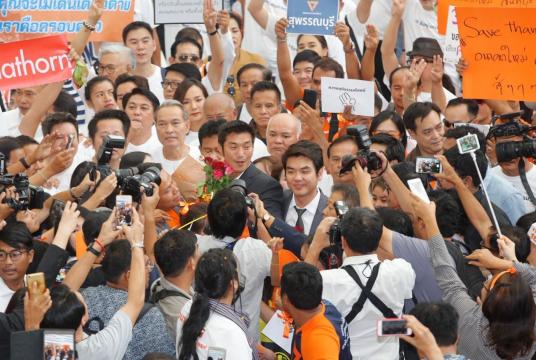 Future Forward leader Thanathorn Juangroongruangkit is surrounded by supporters and reporters when he reports himself to the Election Commission Tuesday./The Nation