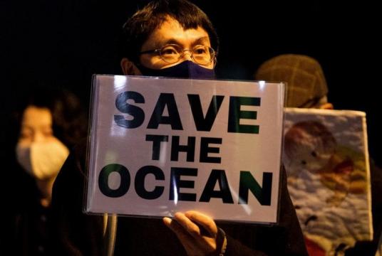 A protestor holds a slogan during a rally against the Japanese government's decision to release treated water from the stricken Fukushima Daiichi nuclear plant into the sea, outside of the prime minister's office in Tokyo on April 13, 2021. (YUKI IWAMURA / AFP)