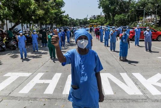 Omandurar Medical College hospital staff gesture as an Indian Air Force (IAF) helicopter drops flower petals to pay tribute to all those involved in the fight against the spread of the COVID-19 coronavirus, in Chennai. (Photo: AFP)