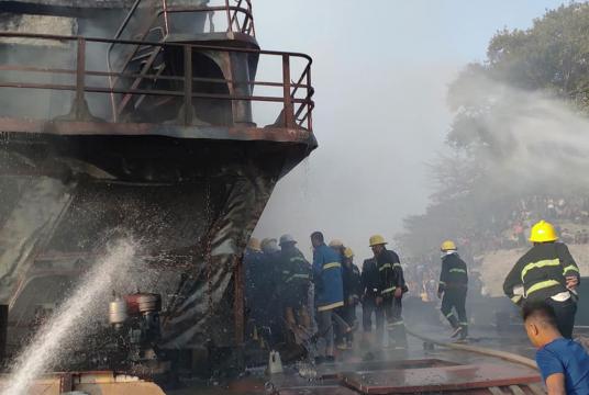 Firefighters are trying to put out the fire on cargo vessel.