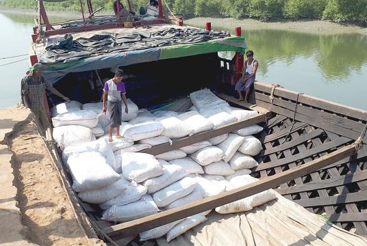 Bags of dried fish are being loaded to powered motor boat docked at Maungdaw port
