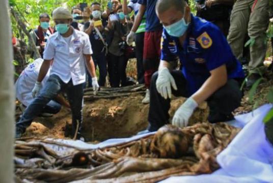 This AFP file photo taken on May 13, 2015 shows rescue workers retrieving human remains from graves near the hillside site where shallow graves containing 26 bodies were found on May 1, close to the town of Padang Besar in the southern Thailand province of Songkhla. Malaysia authorities found mass graves containing the remains of 24 people believed to be human trafficking victims near the border with Thailand on May 23.