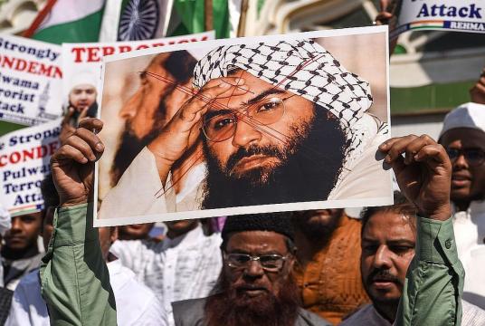 Protesters hold a scratched photo of Jaish-e-Mohammad group chief, Maulana Masood Azhar, as they shout slogans against Pakistan. (File Photo: AFP)