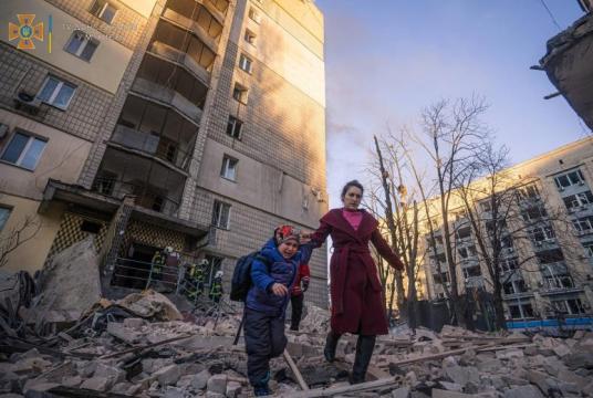 A woman with a child evacuates from a residential building damaged by shelling in Kyiv, on March 16, 2022. PHOTO: REUTERS