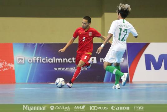 Myanmar player (red) dribbles a ball into opponents' area in Indonesia.
