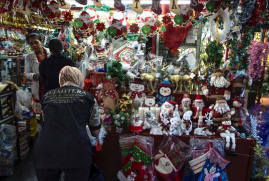 An Indonesian Muslim woman serves her customers at a Christmas decoration shop in Surabaya, Indonesia on Dec 20, 2019. In some places, Christmas celebrations are restricted.PHOTO: AFP