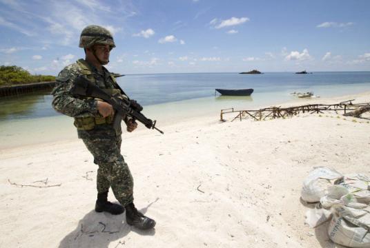 Philippine soldier Tychico Octobre patrols a beach in Pagasa Island (Thitu Island) at the Spratly group of islands in the South China Sea, west of Palawan, on May 11, 2015. The Spratlys are considered a potential Asian flashpoint, and claimant nations have expressed alarm as China has embarked on massive reclamation activity. (AFP FILE PHOTO / POOL / RITCHIE B. TONGO / AFP PHOTO / POOL / RITCHIE B. TONGO)