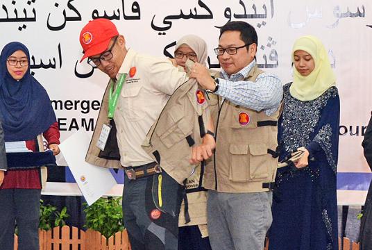  Deputy Executive Director of AHA Centre Arnel Capili helps a participant slip on the ASEAN- ERAT jacket